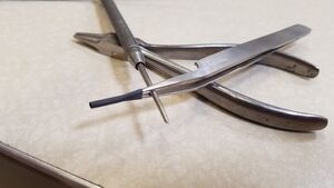 Piece of heatshrink on the end of sharp tweezers with awl wedged between the sharp tweezers forceps.