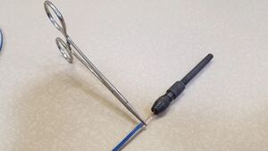 A pin vice being used to twist thermocouple wires in a hemostat.