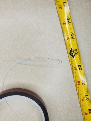 A wire with a clear coating bent back on itself approximately five inches laying on a worktable.